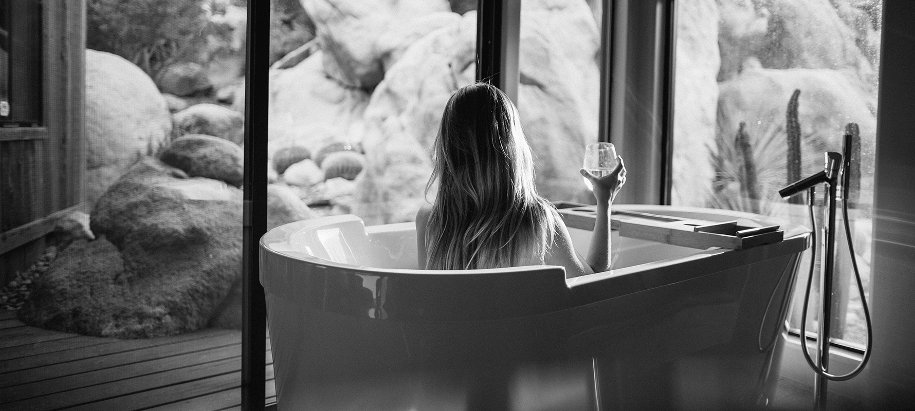 woman sitting in a bath tub holding a glass of a drink